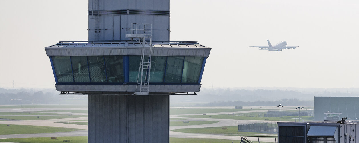 Airplane aeroplane takes off behind a control tower in hazy/misty conditions