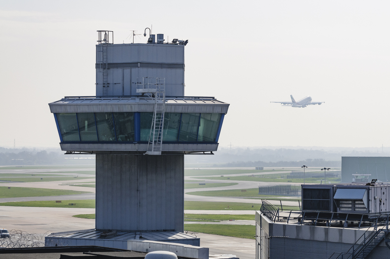 Airplane aeroplane takes off behind a control tower in hazy/misty conditions