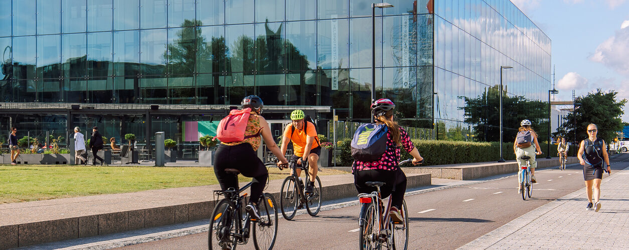 Helsinki, Finland - August 22, 2022: Cyclists in protective helmets ride along bike path in city center on Kansalaistori Square