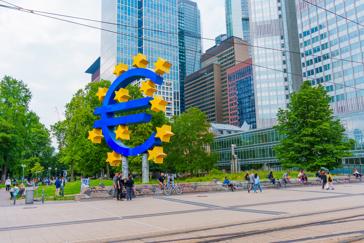 Frankfurt, Germany - June 10, 2025: Vibrant Euro symbol sculpture surrounded by lush greenery and contemporary skyscrapers in Frankfurt, capturing the essence of European finance.