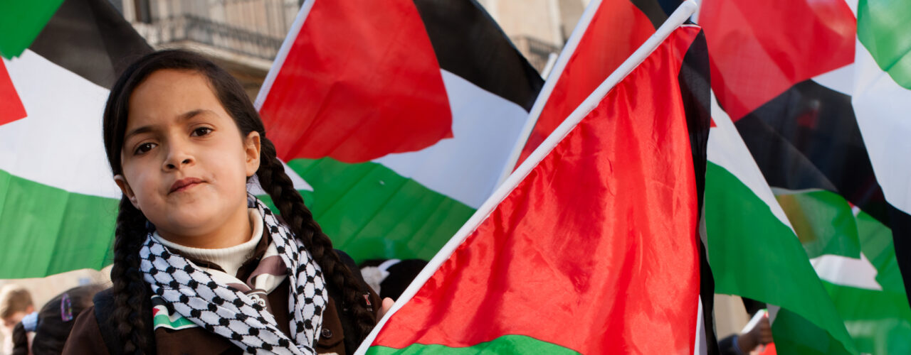 Bethlehem, Occupied Palestinian Territories - November 29, 2012: A girl scout waves a flag during a parade celebrating Palestine's successful bid for "non-member observer state" status at the United Nations, Bethlehem, West Bank.