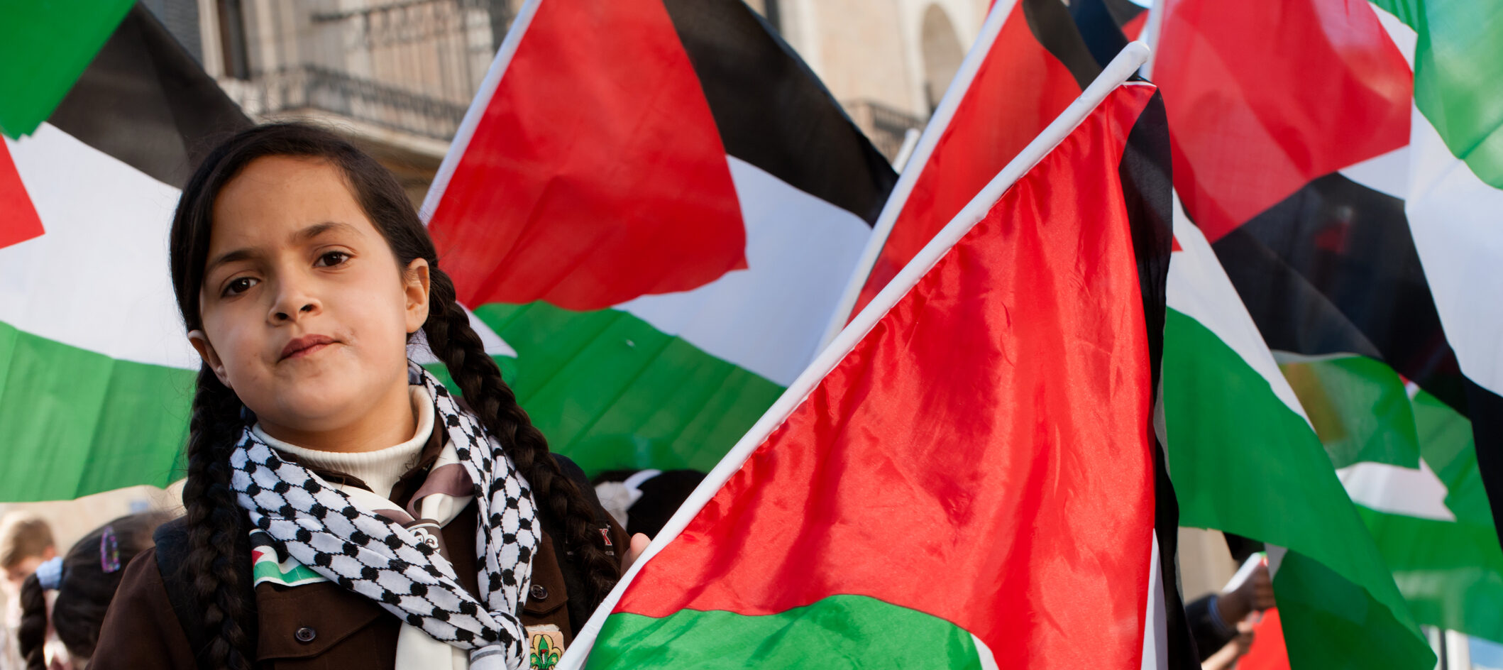 Bethlehem, Occupied Palestinian Territories - November 29, 2012: A girl scout waves a flag during a parade celebrating Palestine's successful bid for "non-member observer state" status at the United Nations, Bethlehem, West Bank.