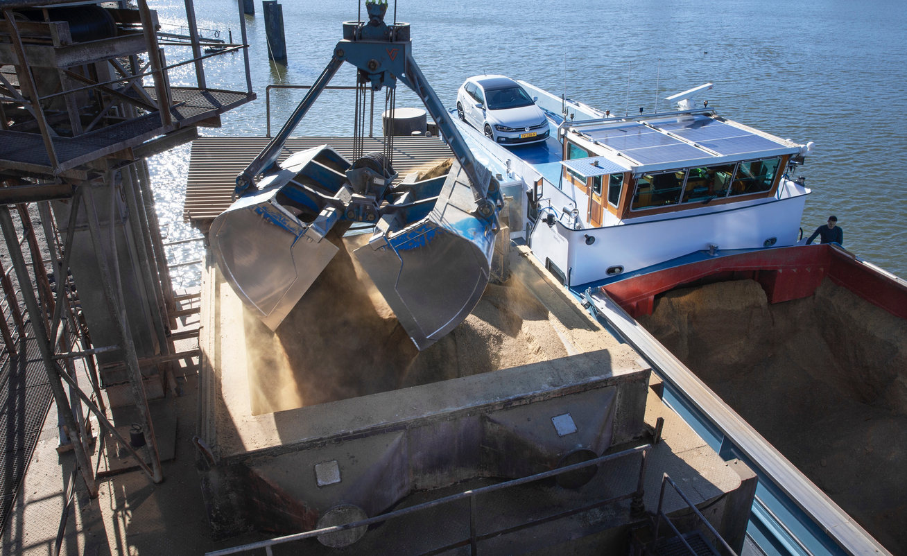 Unloading an inland barge filled with soja by crane. Transport by ship.