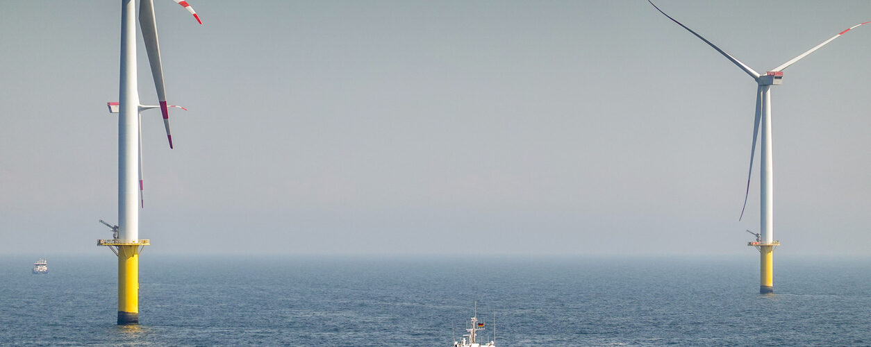 Offshore Wind farm, wind turbines with substation on the horizont in sunset, wavy sea and moody, dramatic sky. Germany, Borkum Riffgrund