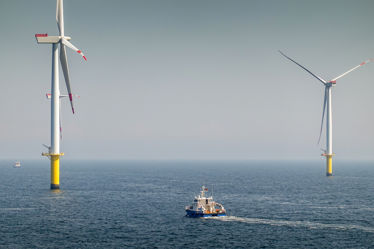 Offshore Wind farm, wind turbines with substation on the horizont in sunset, wavy sea and moody, dramatic sky. Germany, Borkum Riffgrund