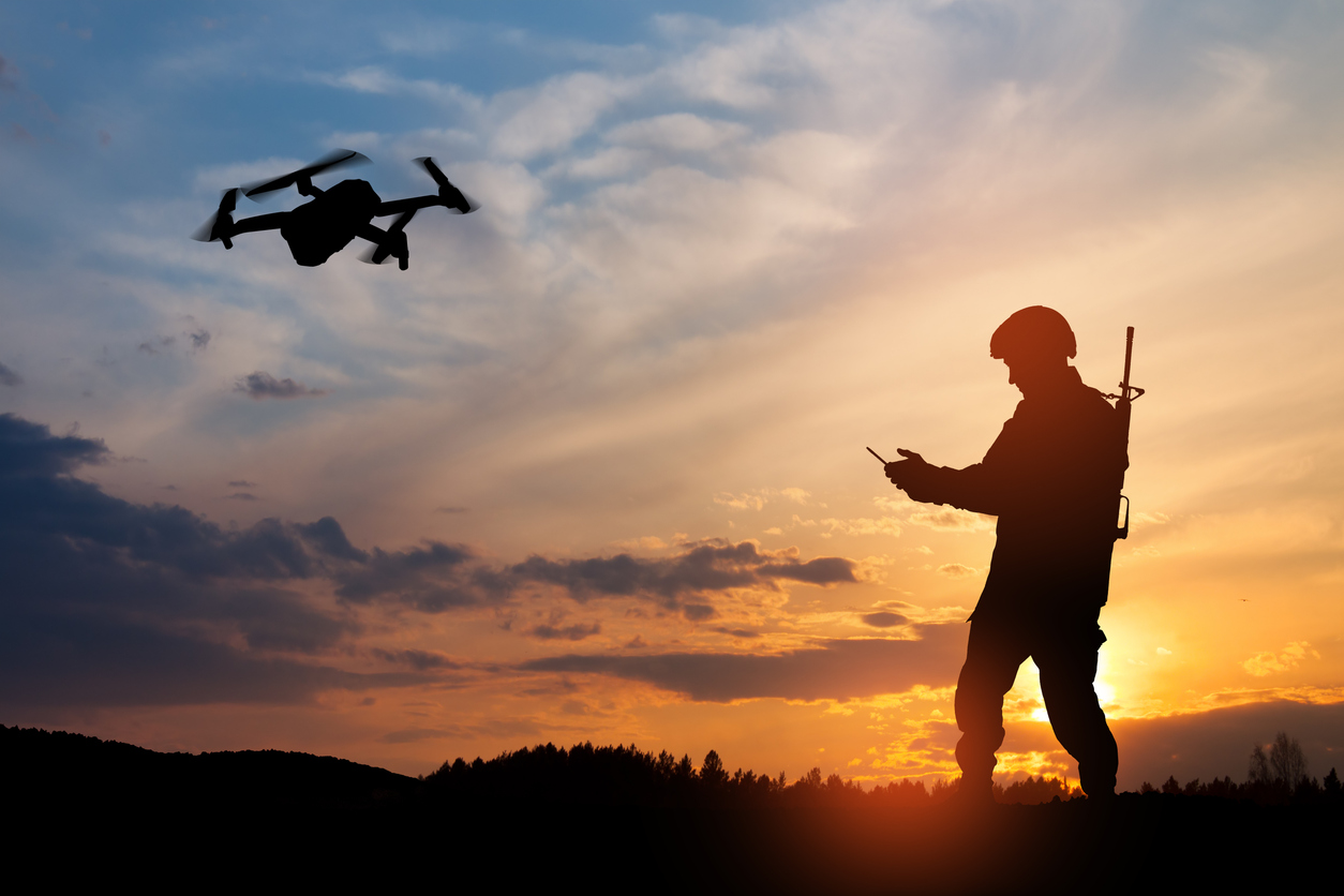 Silhouette of soldier are using drone and laptop computer for scouting during military operation against the backdrop of a sunset. Greeting card for Veterans Day, Memorial Day, Independence Day.
