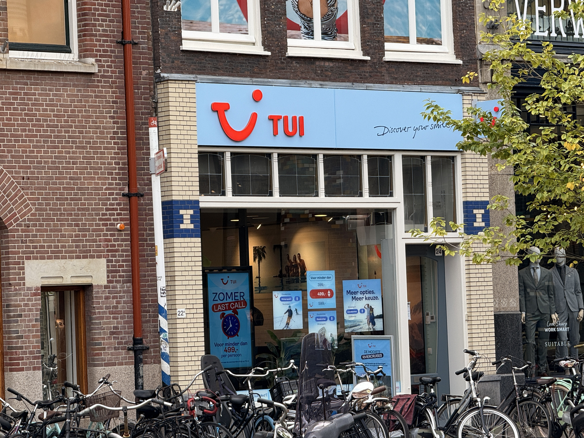 Den Haag, netherlands - September 22 2025: A travel agency displays its sign in a lively city street filled with bicycles and shops on a clear day.