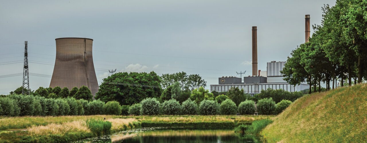 View of canal and gardens with nuclear power plant in background on cloudy day, near the village of Geertruidenberg. A small, friendly place near Aakvlaai Park and Breda. Southern Netherlands.